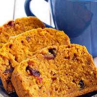 Baked Pumpkin Cranberry Bread on a table with coffee