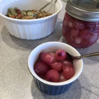 a dish of pearl onions and some pickling spice on the counter
