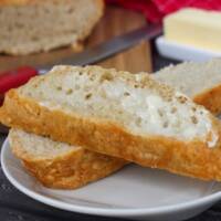 Warm Dutch Oven no knead bread with melted butter sitting on a white plate