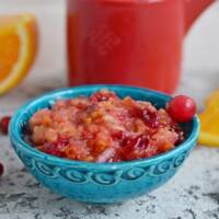 Cranberry Orange Relish in a blue bowl with single cranberry for garnish